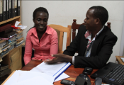 "Helpline Coordinator, Jean Damascene (right), speaks with Paulline (left), who was able to get her family's land back after receiving support from the helpline." 